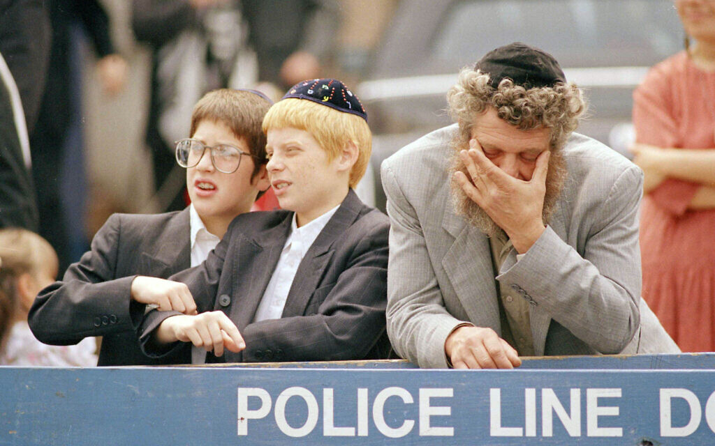 Des Juifs orthodoxes réagissent alors qu'une foule de manifestants noirs en colère s'approche de la synagogue Lubavitcher dans le quartier de Crown Heights à Brooklyn, le 25 août 1991. (Crédit : Mark Lennihan /AP Photo)