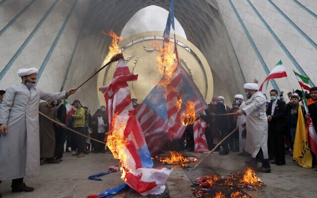 Des religieux brûlent le drapeau américain sous le monument Azadi (liberté) pendant le rassemblement annuel remémorant la révolution islamique de 1979 à Téhéran, le 11 février 2022. (Crédit :  AP Photo/Vahid Salemi)