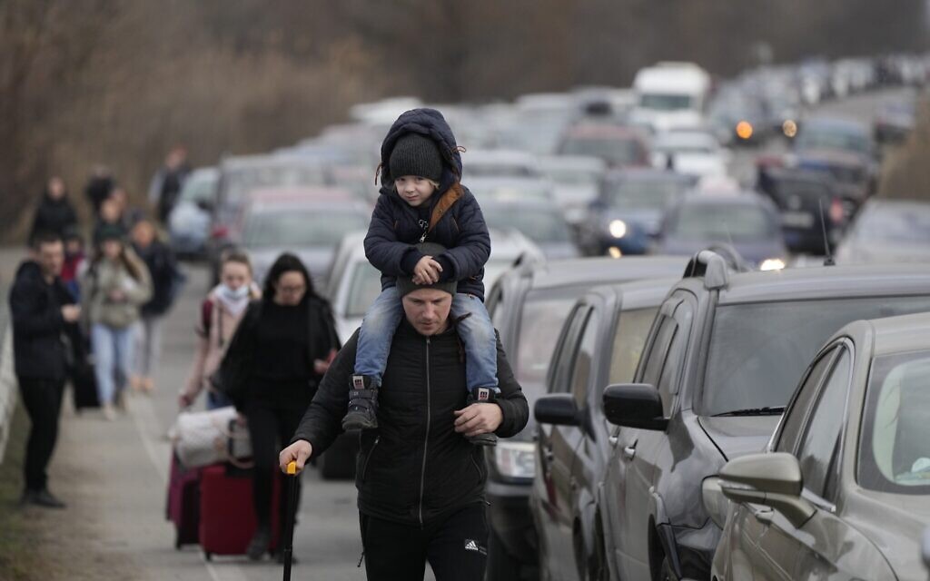 Des réfugiés ukrainiens marchent le long de véhicules faisant la queue pour traverser la frontière entre l'Ukraine et la Moldavie, au poste frontière de Mayaky-Udobne près de Mayaky-Udobne, en Ukraine, samedi 26 février 2022. (Crédit : AP Photo/Sergei Grits)