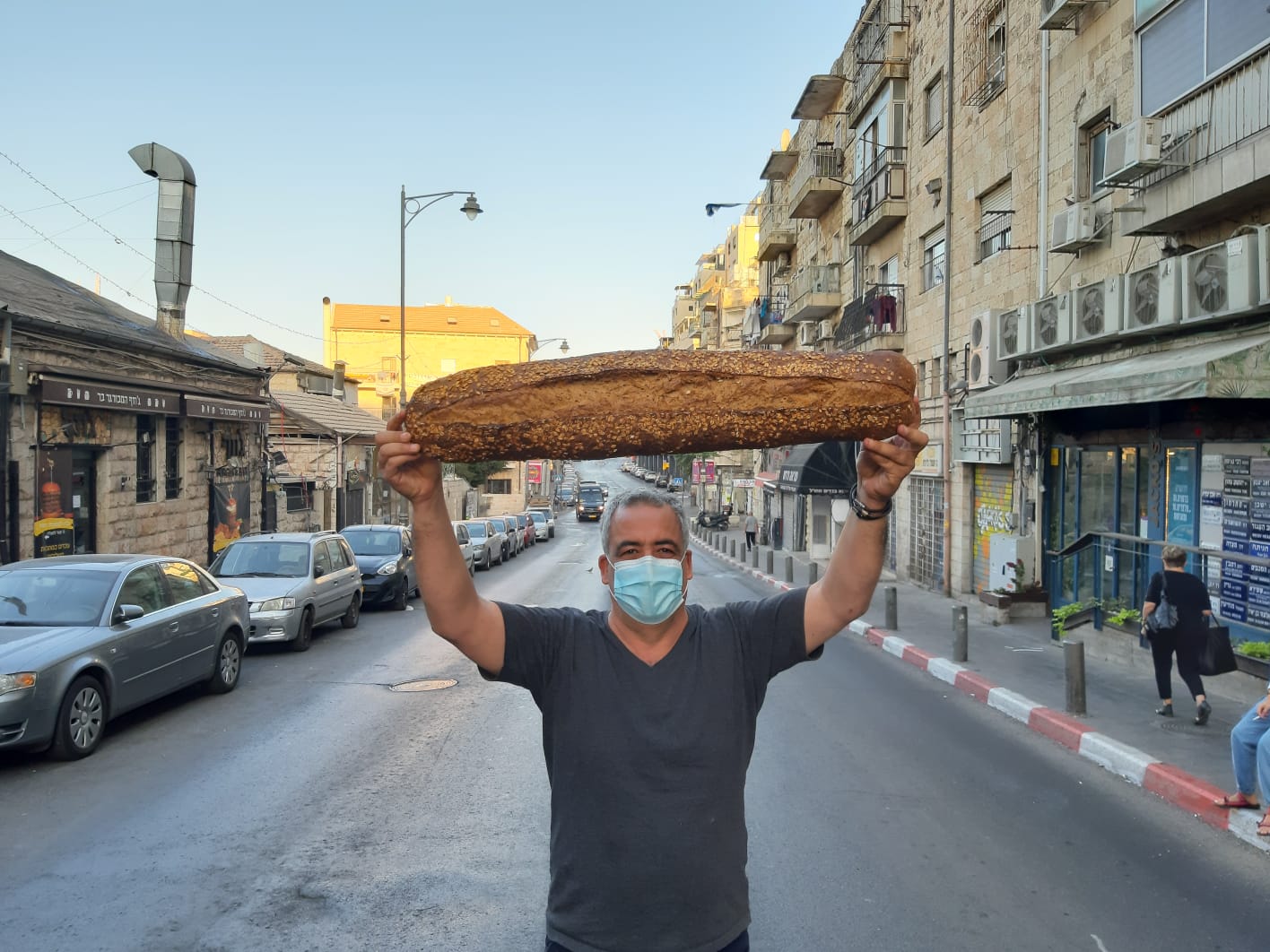 Au milieu de la rue Agrippas, Michel Sultan brandissant un pain de sa fabrication (Crédit : autorisation Michel Sultan)