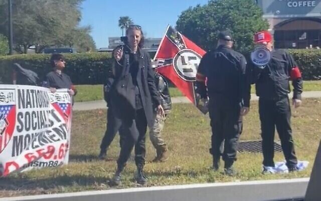 Des manifestants néonazis portant des croix gammées et des bannières du "Mouvement national socialiste" piétinent un drapeau israélien, à Orlando, en Floride, le 29 janvier 2022. (Crédit : capture d'écran : Twitter/Luke Denton)
