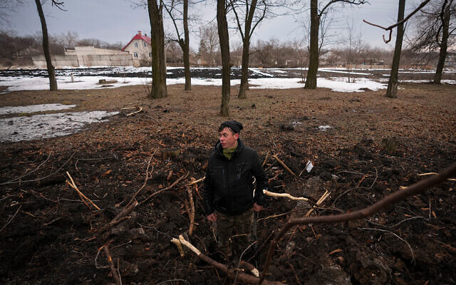 Un homme se tient dans le cratère d'un obus d'artillerie dans l'est de l'Ukraine, le 17 février 2022. (AP Photo/Vadim Ghirda)