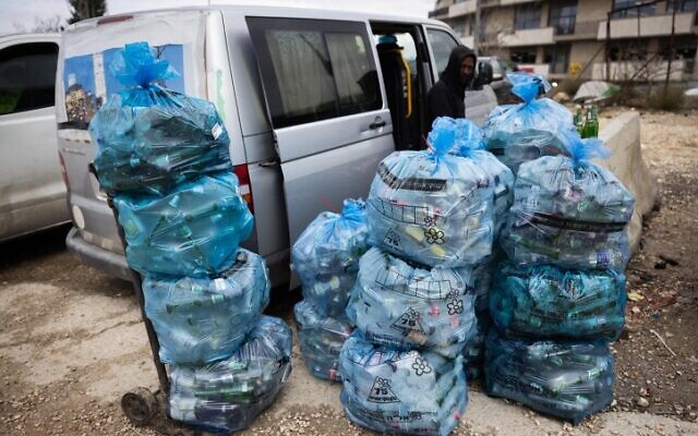 Un homme trie des bouteilles pour le recyclage à Givat Shaul, à Jérusalem, le 1er février 2022. (Crédit : Nati Shohat/Flash90)