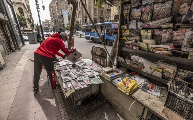 Un vendeur range des journaux dans un kiosque à journaux le long de la rue Kasr al-Aini, dans le centre de la capitale égyptienne, Le Caire, le 17 février 2022. (Crédit : Khaled DESOUKI / AFP)