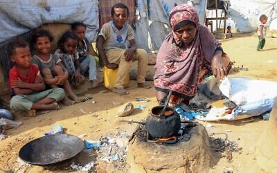 Une femme yéménite cuisine sur un réchaud extérieur en argile dans un camp de fortune pour personnes déplacées dans la province de Hajjah, dans le nord du pays, le 6 mars 2022. (Crédit : ESSA AHMED / AFP)