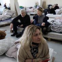 Des réfugiés juifs ukrainiens qui ont fui la guerre dans leur pays attendent dans un hangar de la capitale moldave Chisinau le 15 mars 2022, avant de se rendre à l'aéroport pour embarquer dans un avion pour Israël. (Crédit : Gil Cohen-Magen / AFP)