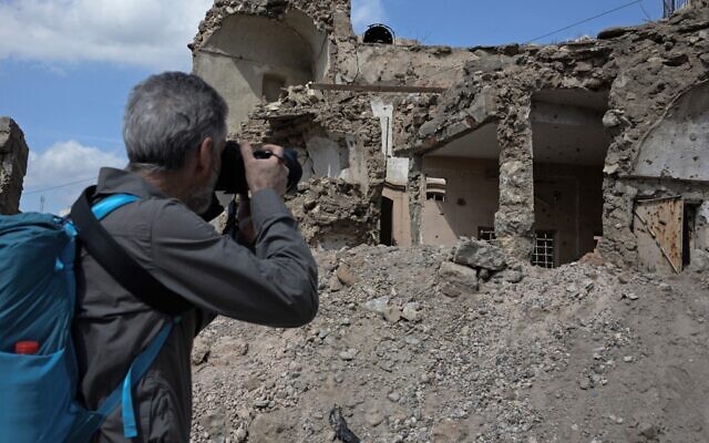 Un touriste prend des photos de la destruction causée par des années de conflit dans la ville de Mossoul, dans le nord de l'Irak, le 12 mars 2022. (Crédit : Zaid AL-OBEIDI / AFP)