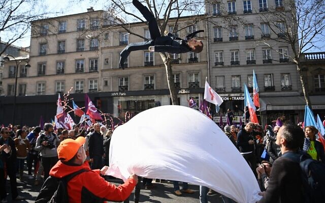 Des manifestants lancent une marionnette du président français Emmanuel Macron lors d’un rassemblement organisé par Jean-Luc Melenchon, candidat du parti "La France insoumise" (LFI) , place de la Bastille, à Paris, le 20 mars 2022. (Crédit : Christophe ARCHAMBAULT/AFP)