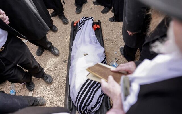 Des Juifs ultra-orthodoxes en deuil se rassemblent autour de la dépouille du rabbin haredi Chaim Kanievsky avant son enterrement au cimetière communautaire de Ponevezh dans la ville de Bnei Barak, près de Tel Aviv, dans le centre d'Israël, le 20 mars 2022. (Crédit : Menahem KAHANA / AFP)