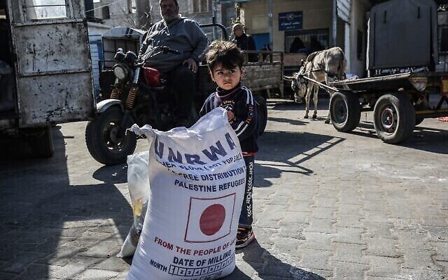 Un enfant à côté d'un sac de farine lors d'une distribution d'aide alimentaire dans un centre de l'UNRWA (l'Office de secours et de travaux des Nations unies pour les réfugiés palestiniens) à Khan Younès, dans la bande de gaza, le 2 février 2020. (Crédit : SAID KHATIB/ AFP/ File)