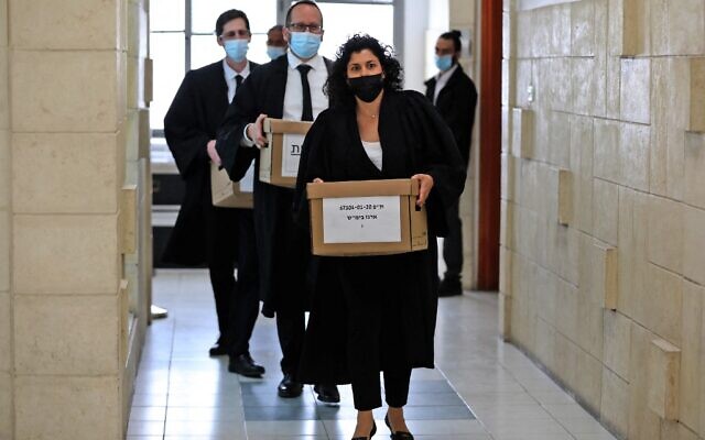 Les procureurs de l'État transportent des cartons de dossiers lors d'une audience du procès pour corruption du Premier ministre Benjamin Netanyahu devant le tribunal de district de Jérusalem, le 5 avril 2021. (Crédit : POOL / AFP)
