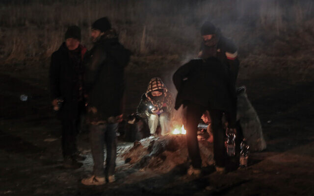 Des étudiants rassemblés autour d'un feu de camp pour se réchauffer au poste frontière de Medyka après avoir fui l'Ukraine, en Pologne, le 28 février 2022. (Crédit : Visar Kryeziu /AP Photo)