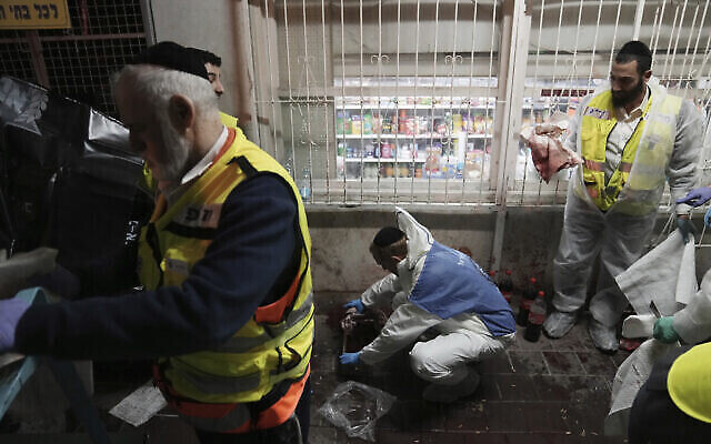 Des bénévoles de la Zaka nettoient le sang dans une rue où un homme armé a ouvert le feu, tuant cinq personnes au total, à Bnei Brak, le 29 mars 2022. (Crédit : AP Photo/Oded Balilty)