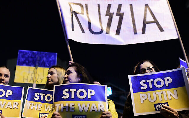 Des manifestants brandissent des pancartes et des drapeaux pendant une manifestation contre l'invasion russe de l'Ukraine à Tel Aviv, le 5 mars 2022. (Crédit : Tomer Neuberg/Flash90)