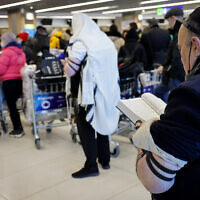 Des Juifs ukrainiens qui ont fui l'invasion russe prient à l'aéroport international de Chisinau en Moldavie, alors qu'ils se dirigent vers Israël, le 6 mars 2022. (Crédit: Nati Shohat/Flash90)