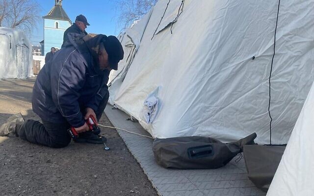 Des travailleurs ukrainiens construisent des tentes pour l'hôpital de campagne israélien en cours de construction à Mostyska, en Ukraine, le 19 mars 2022. (Crédit : Carrie Keller-Lynn/Times of Israel)