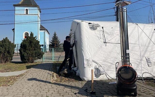 Des travailleurs ukrainiens construisent des tentes pour l'hôpital de campagne israélien en cours de construction à Mostyska, en Ukraine, le 18 mars 2022. (Crédit : Carrie Keller-Lynn/Times of Israel)