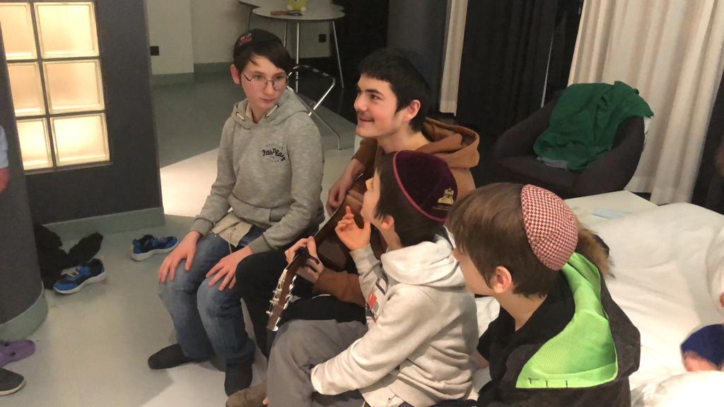 Un moniteur du Habad Camp Yeka joue de la guitare avec ses campeurs, des orphelins juifs d'Odessa, après leur fuite d'Ukraine vers Berlin, mars 2022 (Crédit : avec la permission du Camp Yeka)