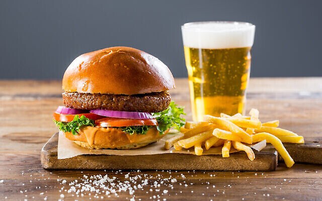 Un hamburger de boeuf cultivé produit par la société israélienne Future Meat, servi avec des frites et une bière. (Crédit : Future Meat)