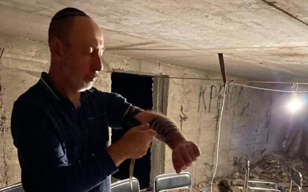 Un homme juif met des tefillin, des phylactères de prière, avant de prier dans un abri anti-aérien à Marioupol, en Ukraine, au cours de la première semaine de la guerre de la Russie contre l'Ukraine. (Crédit : JTA)