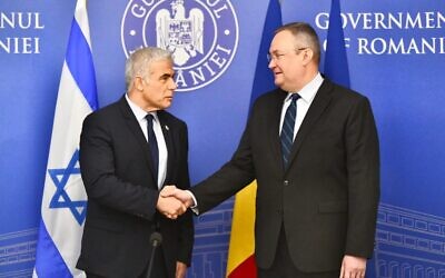Le ministre des Affaires étrangères Yair Lapid rencontre le Premier ministre roumain Nicolae Ciucă à Bucarest, le 13 mars 2022. (Crédit : Shlomi Amsalem/GPO)