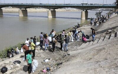 De jeunes volontaires irakiens participent à une campagne de nettoyage sur la rive du fleuve Tigre dans le district d'Adhamiyah de la capitale Bagdad, le 11 mars 2022. (Crédit : Sabah ARAR / AFP)