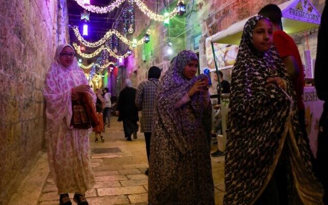 Des Palestiniennes se promènent dans la Vieille Ville de Jérusalem, au premier soir du Ramadan, le 2 avril 2022. (Crédit :  Menahem KAHANA / AFP)