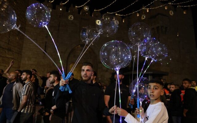 Des Palestiniens vendent des ballons aux abords de la porte de Damas, dans la Vieille Ville de Jérusalem, au premier soir du Ramadan, le 2 avril 2022. (Crédit :  Menahem KAHANA / AFP)