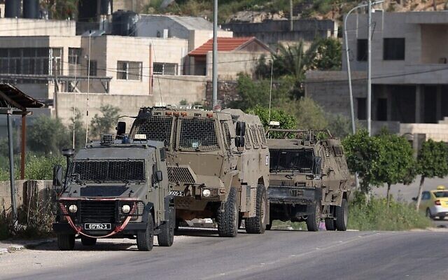Des véhicules de l'armée israélienne)à l'entrée du camp de réfugiés palestiniens de Nur Shams pendant un raid, le 10 avril 2022. (Crédit :JAAFAR ASHTIYEH / AFP)