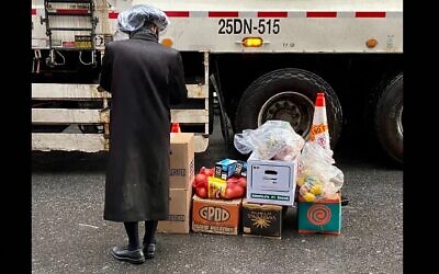 Un orthodoxe Satmar se porte volontaire pour distribuer de la nourriture offerte par le Met Council dans un centre de distribution du Brooklyn Navy Yard géré par les United Jewish Organizations of Williamsburg, le 10 avril 2022. (Crédit : Jacob Henry/JTA)