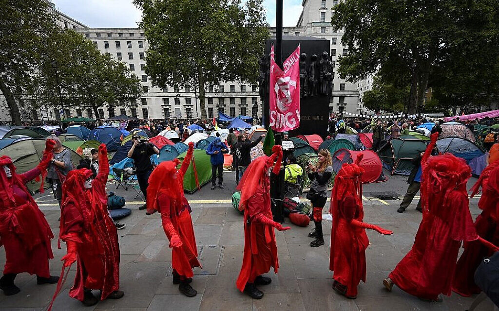 Des militants en costumes rouges protestent sur Whitehall, près de Downing Street, lors de la deuxième journée de manifestations sur le changement climatique du groupe Extinction Rebellion, dans le centre de Londres, le 8 octobre 2019. (Crédit : Ben Stansall/AFP)