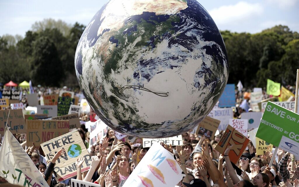 Un grand globe gonflable est ballotté dans la foule entre des milliers de manifestants, dont de nombreux écoliers, rassemblés pour demander des mesures de protection contre le changement climatique rassemblent à Sydney, le 20 septembre 2019. (Crédit : Rick Rycroft /AP)
