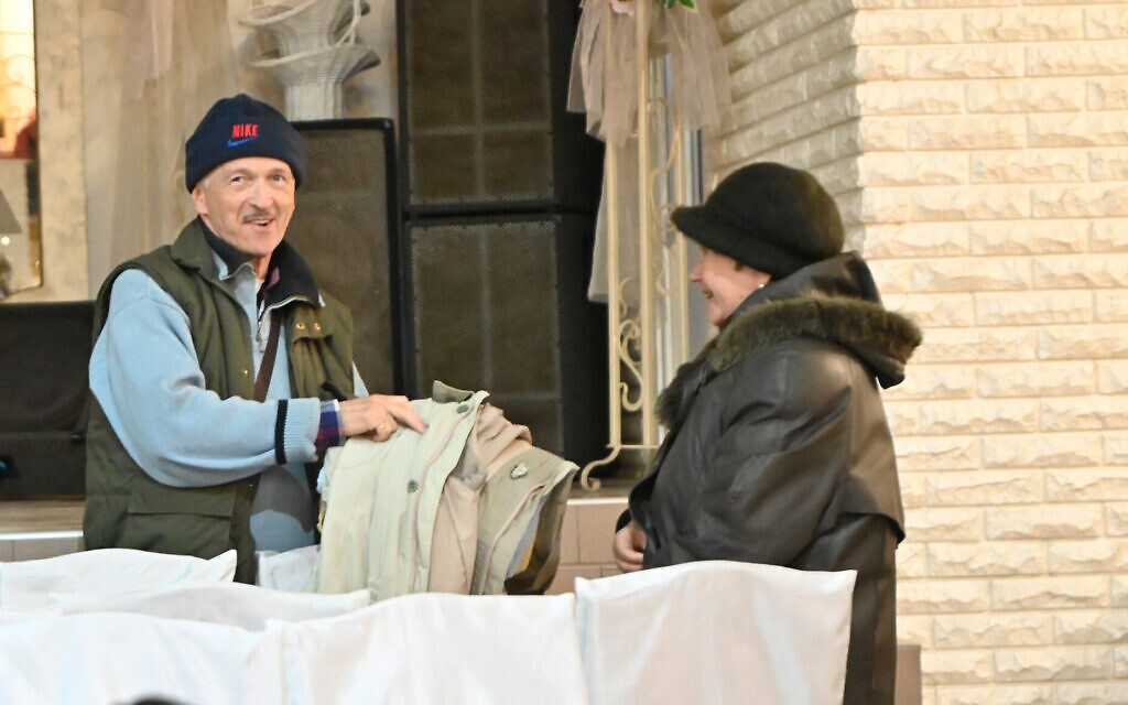 Un homme demande à une femme de réparer un manteau  au camp de réfugiés d'Irshava, en Ukraine, le 5 avril 2022. (Crédit :Cnaan Liphshiz/ JTA)