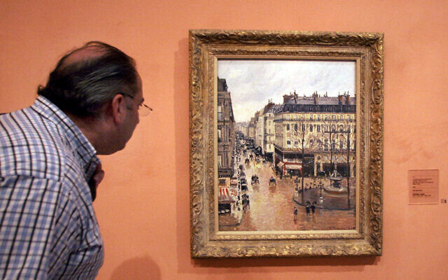 Cette photo d'archive du 12 mai 2005 montre un visiteur regardant le tableau impressionniste intitulé "Rue St.-Honoré, après-midi, effet de pluie" peint en 1897 par Camille Pissarro, exposé au musée Thyssen-Bornemisza à Madrid. (Crédit: AP Photo/Mariana Eliano, Dossier)