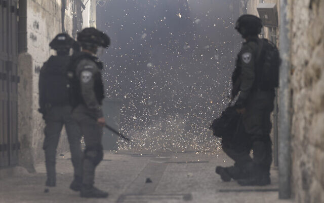 Des Palestiniens jetant des feux d'artifice sur des policiers israéliens dans la Vieille Ville de Jérusalem, le 17 avril 2022. (Crédit : Mahmoud Illean/AP)