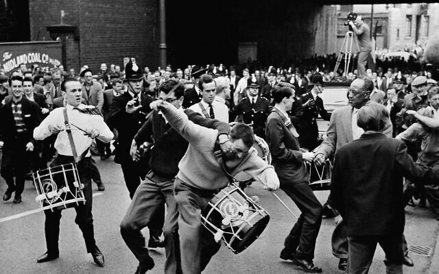 Un spectateur furieux attaque un joueur de tambour fidèle au leader fasciste britannique, Sir Oswald Mosley, à la tête du mouvement syndical britannique de droite extrémiste, lors d’une marche à travers Manchester, en Angleterre, le 29 juillet 1962. La quarantaine de manifestants ont essuyé des jets de pierres et de tomates avant d’être physiquement  pris à parti par la foule. (Crédit : AP Photo)