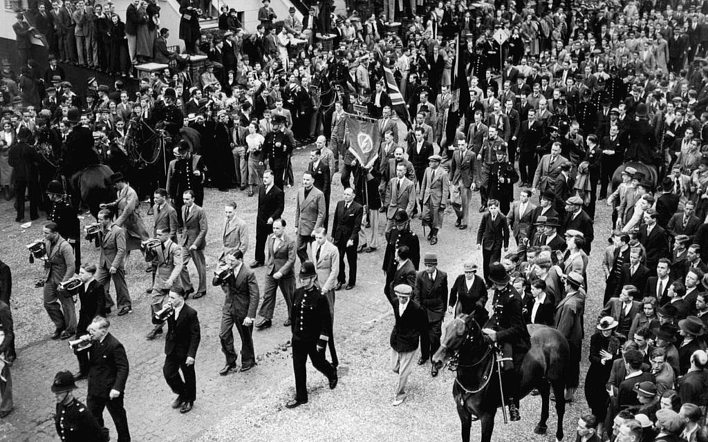 Illustration : Départ de la procession de l’Union Britannique des Fascistes quittant Islip Street à Kentish Town, Londres, en route vers Trafalgar Square, Londres, Angleterre, le 4 juillet 1937. Sir Oswald Mosley est en costume de couleur claire, entouré de trois personnes, dans l'axe du drapeau fasciste. (Crédit : AP Photo)