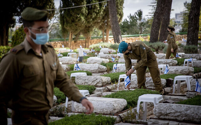 Des soldats israéliens placent des drapeaux israéliens sur les tombes de soldats morts au combat au cimetière militaire du Mont Herzl à Jérusalem, le 11 avril 2021. (Crédit: Yonatan Sindel/Flash90)