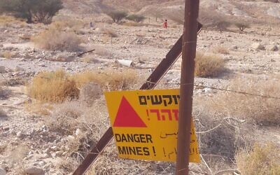 Un panneau avertissant de la présence d'un champ de mines près du Nahal Tamar où deux sœurs, ici en arrière-plan, sont entrées par mégarde, le 13 avril 2022. (Crédit : Arava Rescue Services)