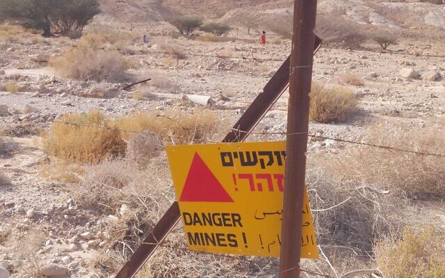 Un panneau avertissant de la présence d'un champ de mines près du Nahal Tamar où deux sœurs, ici en arrière-plan, sont entrées par mégarde, le 13 avril 2022. (Crédit : Arava Rescue Services)