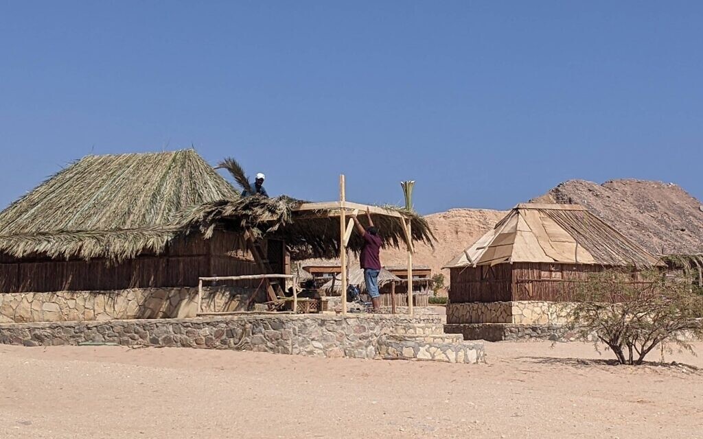 Des ouvriers finissent de construire des cabanes rénovées sur la plage à Ras Shaitan, dans le Sinï, le 5 novembre 2021. (Crédit : Melanie Lidman/Times of Israel)