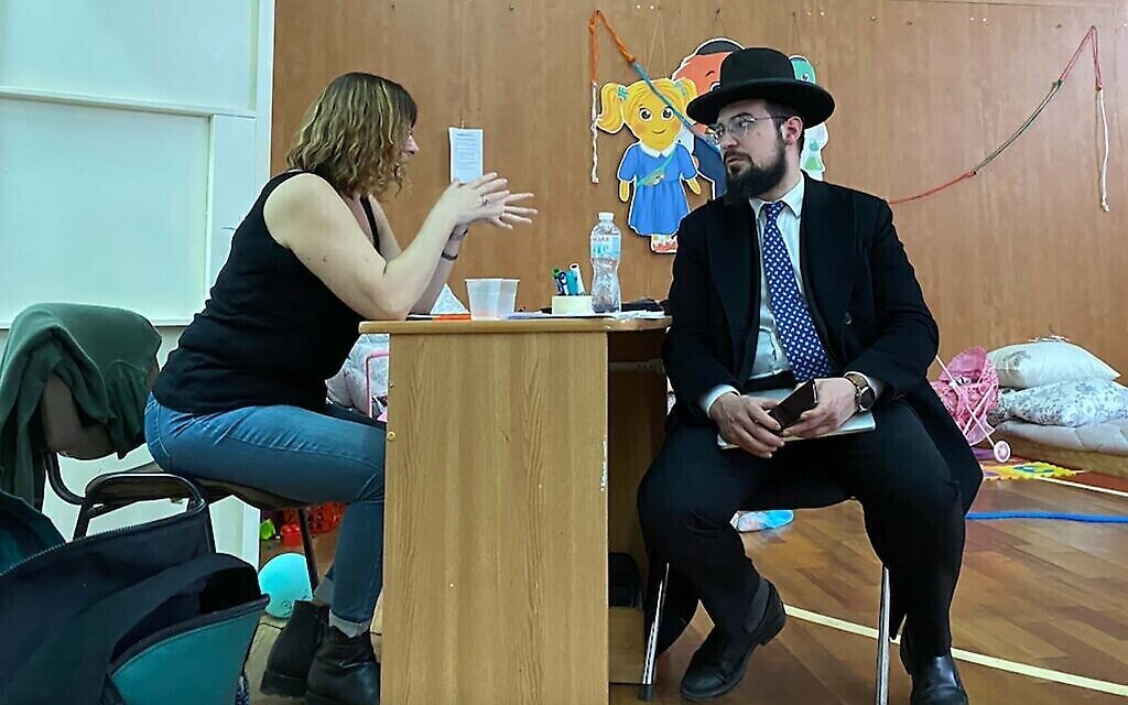 Le rabbin Shimshon Izakson s'entretient avec un travailleur humanitaire dans une salle de sport au centre-ville de Chisinau, en Moldavie. (Crédit : Jacob Judah via la JTA)
