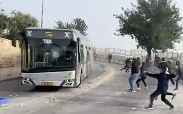 Des Palestiniens jettent des pierres sur un bus israélien, devant la Vieille Ville de Jérusalem le 17 avril 2022. (Crédit : Capture d’écran Twitter)