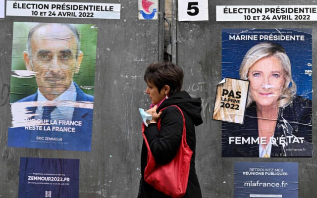 Un piéton passe devant les affiches de campagne des candidats à l'élection présidentielle française Eric Zemmour, à gauche, et Marine Le Pen avant le premier tour de l'élection présidentielle française à Paris, le 7 avril 2022. (Crédit: Emmanuel Dunand/AFP/Getty Images via JTA)