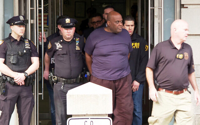 Des agents des forces de l'ordre conduisent Frank James, 62 ans, suspect d'avoir tiré dans le métro, hors du 9e arrondissement du département de police de New York, dans l'arrondissement de Manhattan à New York, le 13 avril 2022. (Crédit: AP Photo/Ted Shaffrey)