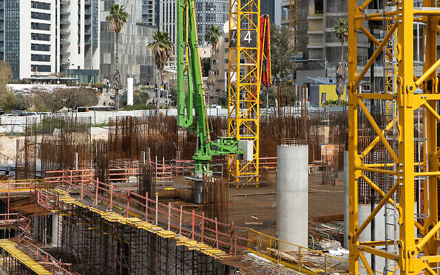 Des ouvriers travaillent sur un chantier de construction d’un gratte-ciel à Tel-Aviv, en Israël. Illustration, avril 2022 (Crédit : Roman Mykhalchuk via iStock de Getty Images)