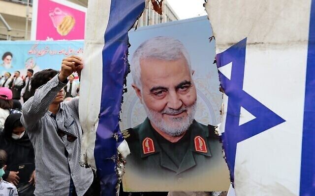 Des Iraniens se préparent à mettre le feu à un drapeau israélien près d'une photo de feu le général Qasem Soleimani pendant la journée d'Al-Quds à Téhéran, le 29 avril 2022. (Crédit : AFP)