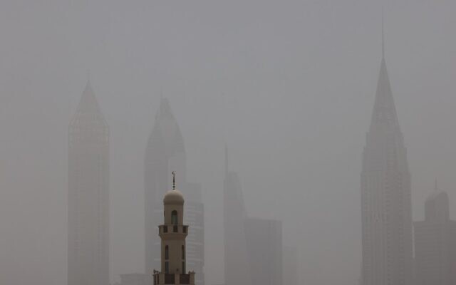Cette photo prise le 18 mai 2022 montre une vue de la brume obscurcissant la ligne d'horizon de l'émirat de Dubaï, dans le Golfe, avec une mosquée au premier plan, pendant une forte tempête de sable. (Crédit : Giuseppe CACACE / AFP)