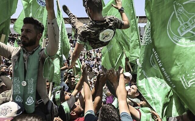 Un étudiant palestinien portant une chemise du Hamas est soulevé lors d’un rassemblement en soutien au groupe, lors de la célébration d'une victoire aux élections étudiantes à l’Université de Birzeit, dans la banlieue de Ramallah, le 19 mai 2022. (Crédit : Abbas Momani/AFP)
