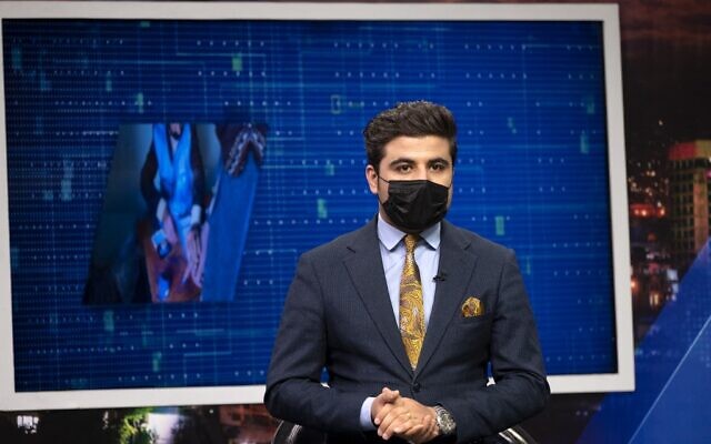 Nisar Nabil, présentateur de TOLOnews, portant un masque noir, parle pendant une émission en direct à la station de télévision Tolo à Kaboul, le 25 mai 2022. (Crédit : Wakil KOHSAR / AFP)